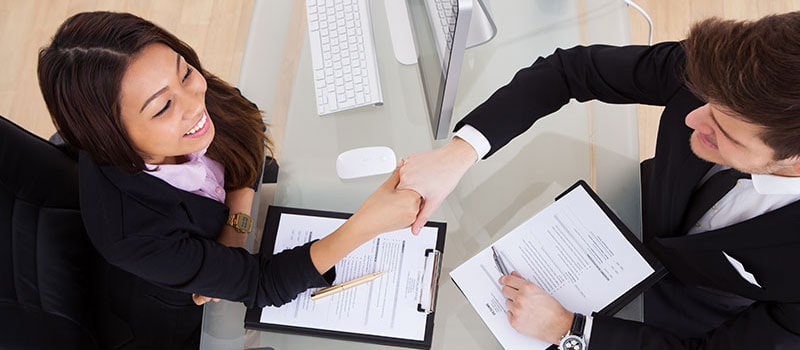 two people shaking hands over desk